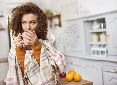 裹着毯子喝热茶的年轻女人图片