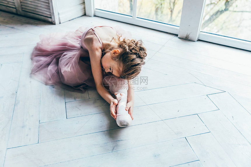 舞蹈课上的年轻古典芭蕾舞演员女孩身着粉色短裙的美丽优雅芭蕾舞女演员在白光大厅的大窗户附图片