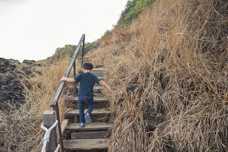 健康的小男孩用人字拖攀爬和远足到山顶图片