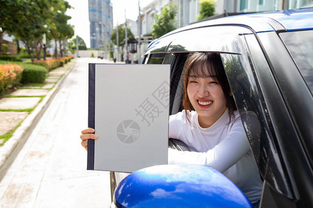 持有政策汽车簿和坐在车里的亚洲青年妇女图片