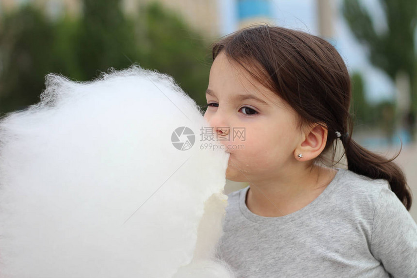 带着马尾辫的小女孩想在城市庆典上咬一球棉花糖图片