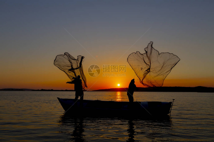 日落海滩上的Silhouette渔民网捕鱼图片