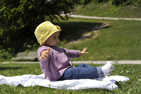 可爱的小女孩黄帽子在夏天坐在草地上图片
