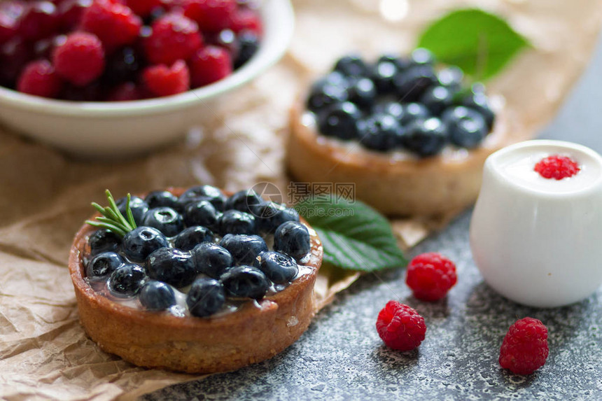 灰色表面有蓝莓新鲜草莓和酸奶油的塔饼图片