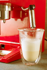 红色复古风格的咖啡机和带鲜奶的拿铁杯特写图片