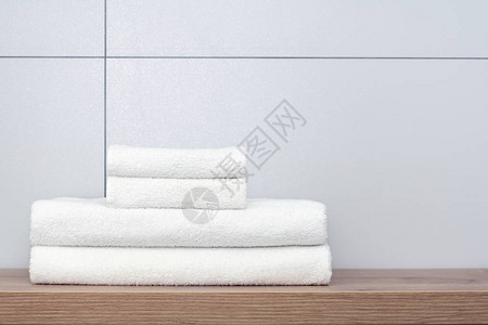 两条大两条折叠整齐的白毛巾放在木架子上图片