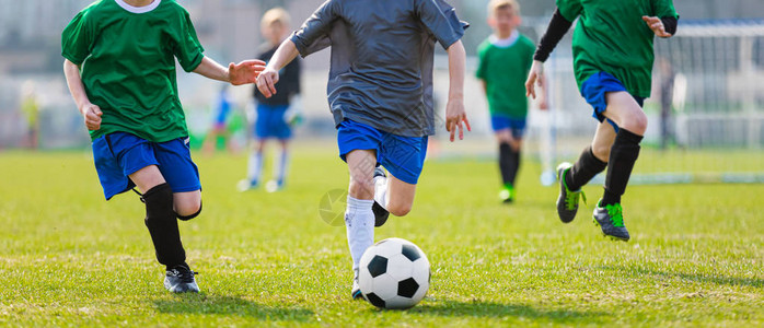 踢足球的男孩运行足球员决斗的五名少年足球员足球场和足图片