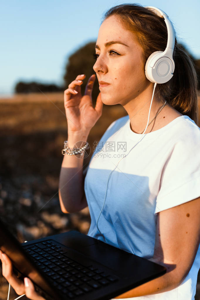 年轻妇女用她的笔记本电脑监听耳机对外通信图片