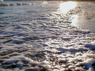 日落时海浪上的太阳眩光图片