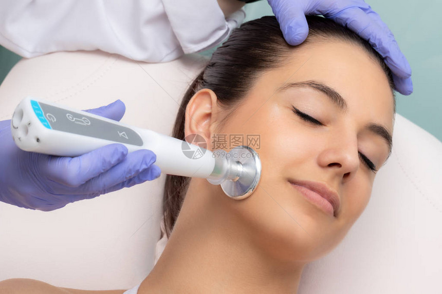 近距离的治疗师用平头等离子笔做面部间疗程女人脸颊上的电动脉冲刺图片