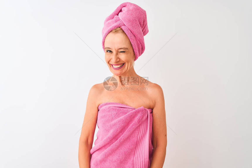 中年妇女洗完澡后穿着浴巾站在孤立的白色背景上眨着眼看着镜头图片