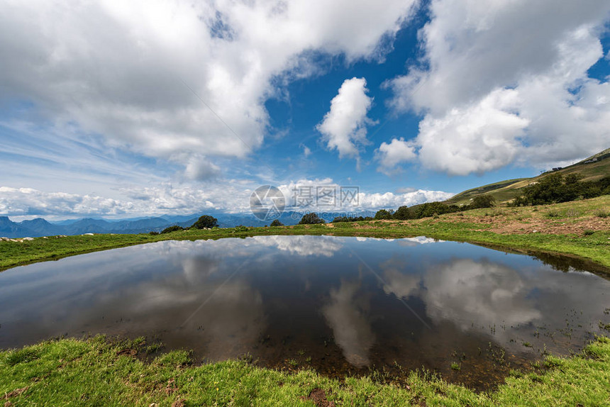 天空和云彩反射的牲畜小湖巴尔多山维罗纳附近的意大利阿尔卑斯山和意大利威尼托南图片