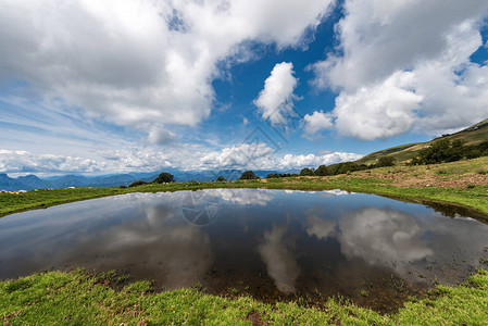 天空和云彩反射的牲畜小湖巴尔多山维罗纳附近的意大利阿尔卑斯山和意大利威尼托南图片
