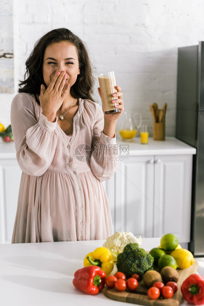 快乐的孕妇拿着杯子带着美味图片