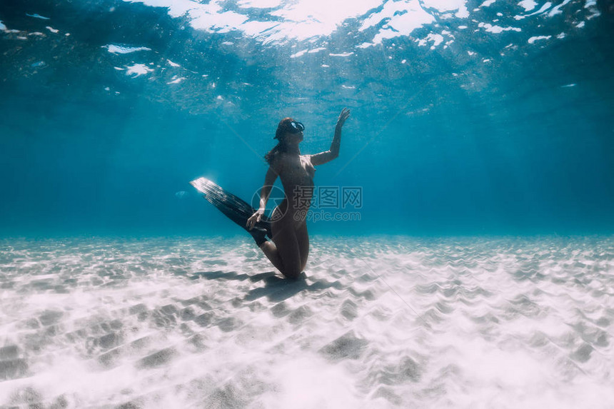 女自由潜水员其鳍在沙海上漂浮图片