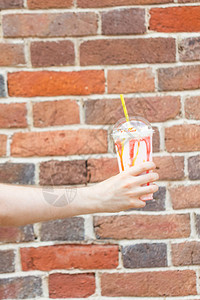 一位身份不明的青年男子手里握着一个石墙上的牛奶果汁鸡尾酒图片