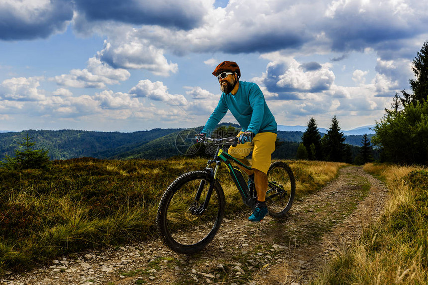 骑自行车的骑手在日落山区森林景观上骑车图片