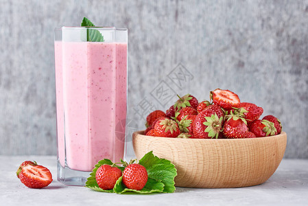 玻璃罐中的草莓冰沙和灰色背景的木碗中的新鲜草莓图片
