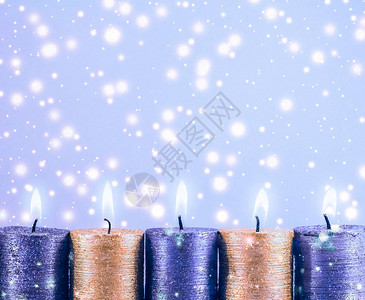 冬季庆祝活动和新年夜概念圣诞蜡烛和蓝底的闪亮雪花图片