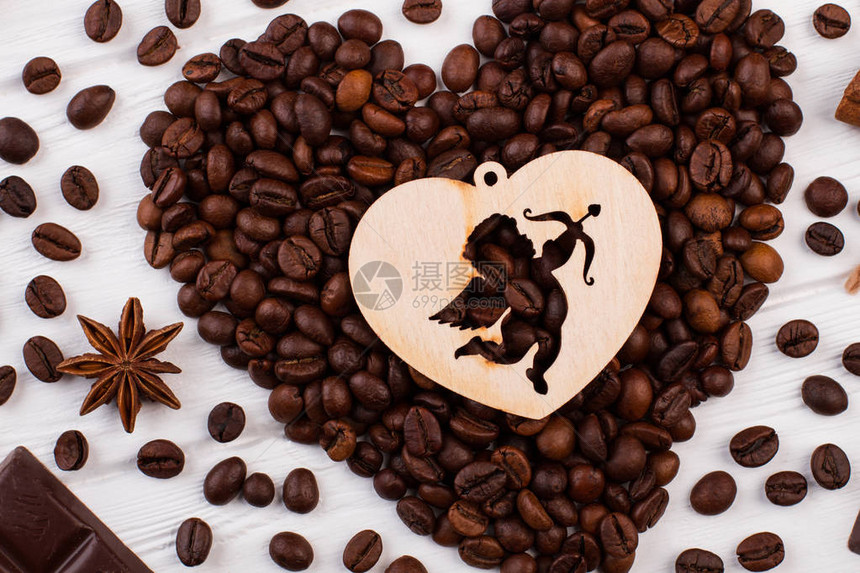 心形咖啡豆和胶合板心与丘比特烤咖啡豆在白色木制背景上形成心图片
