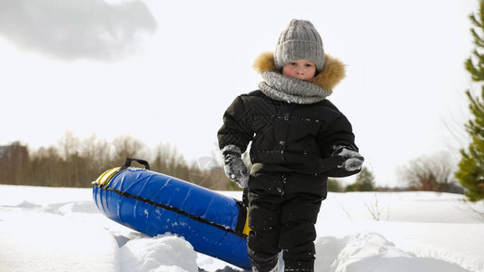 他走路拉着浴缸滑到冬季公园的雪地里图片