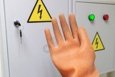 橡胶绝缘手套在车门前的电门上的警示牌上电工作场所用电的背景图片
