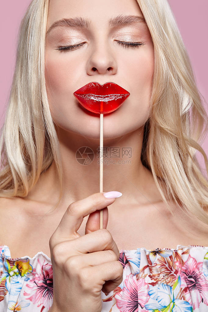 闭上眼睛的金发女人吻糖果红色女嘴唇塑造棒图片