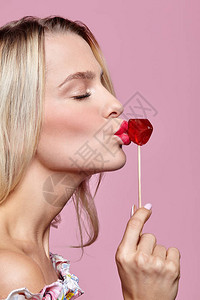 闭上眼睛的金发女人吻糖果红色女嘴唇塑造棒图片