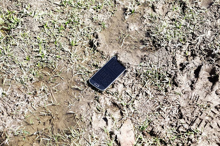 一部带水的棕色泥浆中的手机图片