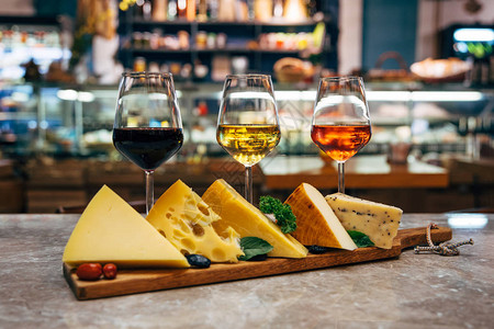 杯酒和奶酪餐厅桌子上的各种或各种类型的奶酪和酒杯桌上的红玫瑰和黄酒或香槟图片