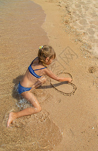 孩子在沙滩上画沙子图片