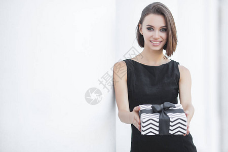 有魅力的年轻女人拿着箱子笑着带着黑色礼物图片
