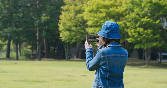 妇女使用移动电话在农村拍摄照片图片