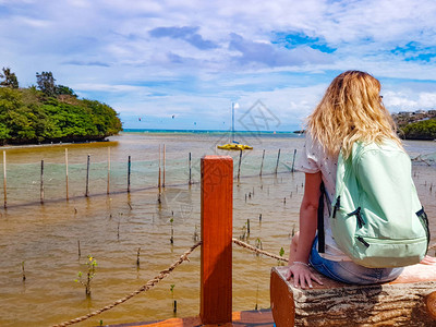 背着包的女孩坐在菲律宾博拉凯岛岸边的长凳上图片