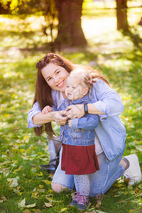 怀孕的年轻母亲在秋天公园与女儿一起玩耍图片