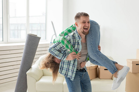 乔迁新居素材年轻的疯狂夫妇穿着牛仔裤在搬家期间在他们的新公寓里玩得开心乔迁新居理背景