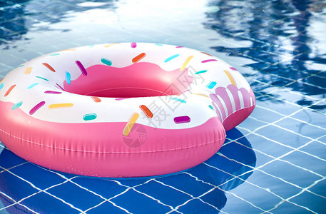 在游泳池游泳的充气配件以充气大粉红色甜圈的形式图片