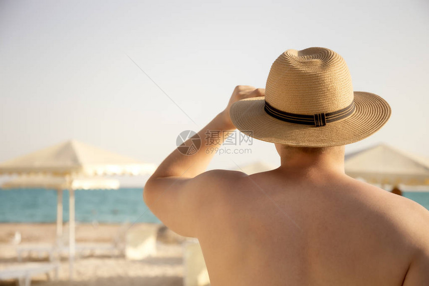 戴帽子看海的有肌肉魅力的年轻男子图片