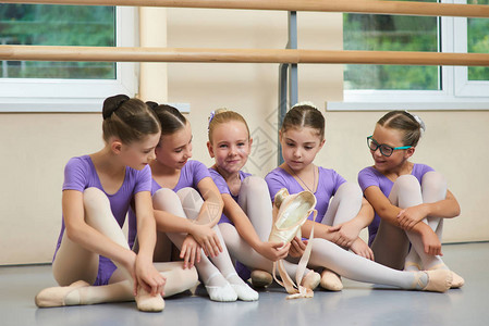 美丽的白种人芭蕾舞女演员与新拖鞋年轻的芭蕾舞演员坐在地板上专图片
