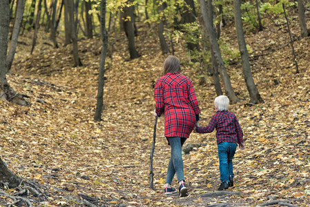 妈和小儿子在秋天的森林里散步背影图片