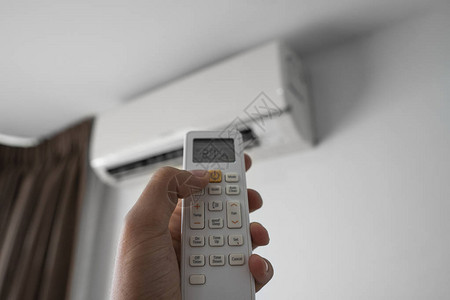 勒芒手使用遥控器手持rc和调节安装在白墙上的空调温度室内舒适温度健图片