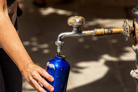 在炎热的夏日用水龙头的水瓶装满一个水瓶时图片
