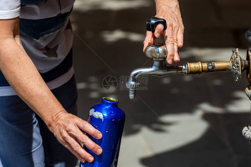 在炎热的夏日用水龙头的水瓶装满一个水瓶时图片