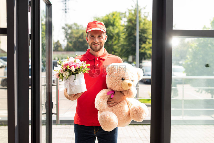 拿着泰迪熊和鲜花的快乐送货员图片