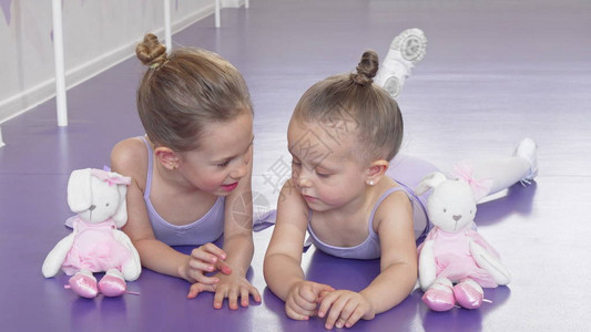 两个小芭蕾舞演员在芭蕾舞学校的地板上练习后休息图片