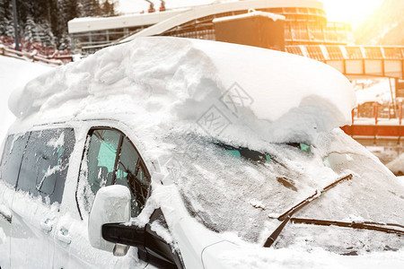 汽车在大雪后覆盖着厚的雪层的街道上极端暴风雪后果车辆挡风玻璃与冻图片