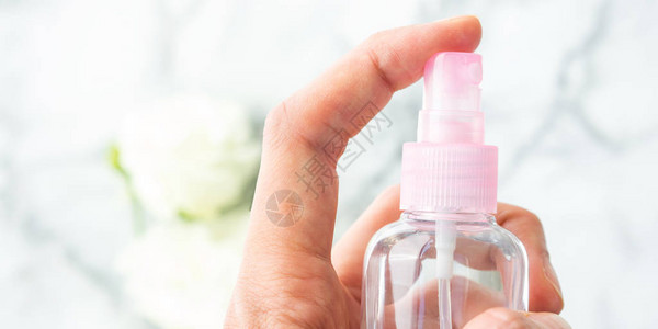 妇女用手从小粉红色喷雾瓶中喷出液体图片
