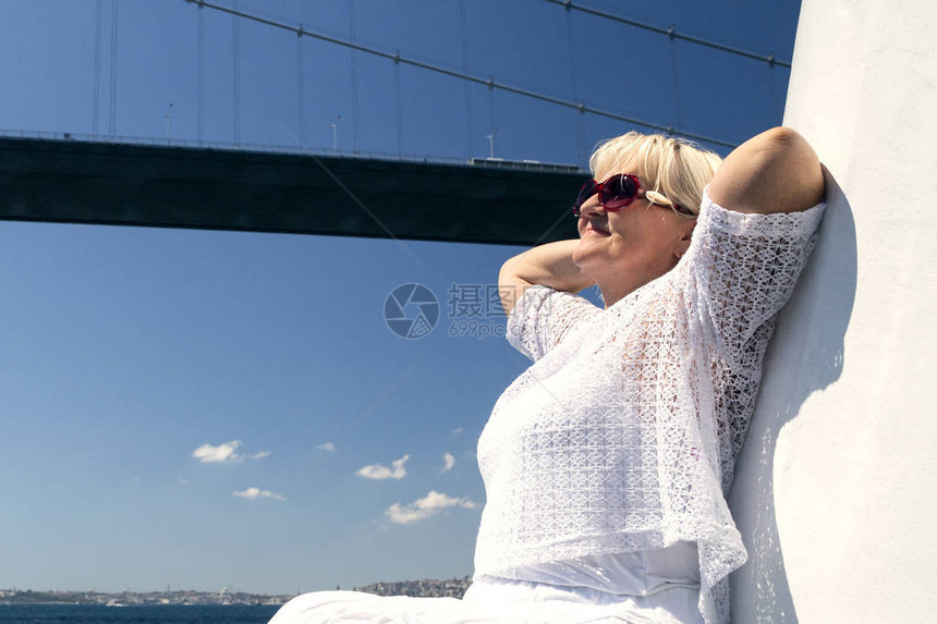 在大白船或游艇上的太阳镜上微笑着有吸引力的女人巡游旅行和积极退休者冒险背景是美图片