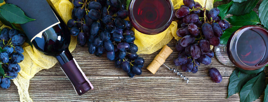 酒杯配红酒瓶子开瓶器蓝葡萄木桌上的叶子带有复制空间的葡萄酒背景顶视图图片