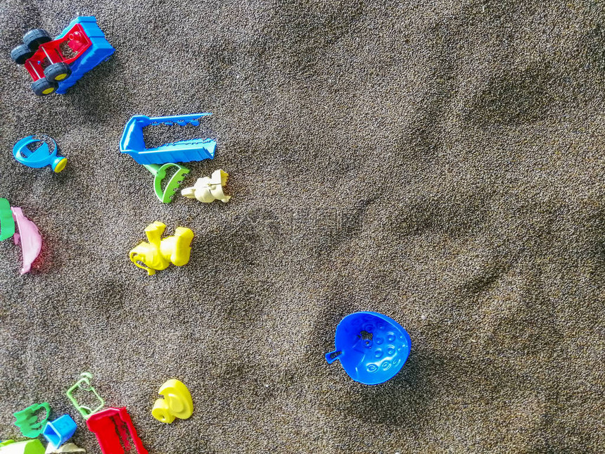 沙地上的多色塑料玩具在沙滩上和沙滩上玩耍的儿童玩具铲斗铲子和耙子图片